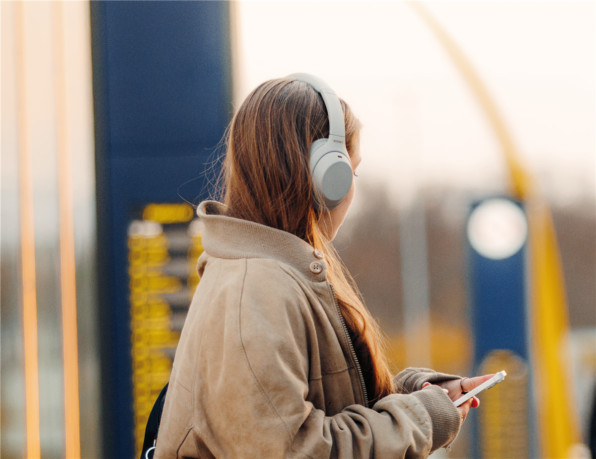 Bilde av ungdom med hodetelefoner som venter på bussen - Klikk for stort bilde